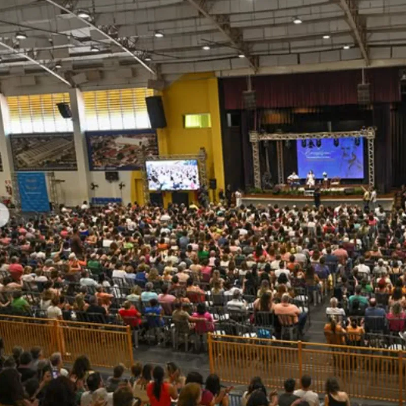 Auditório do congresso lotado, com palco iluminado e telões
