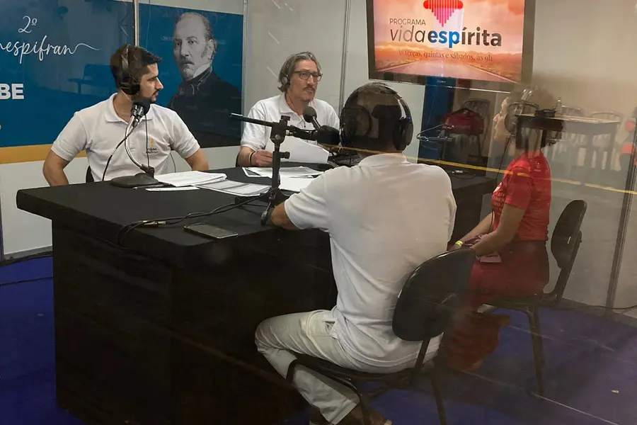 Apresentadores e convidada ao redor da bancada do estúdio